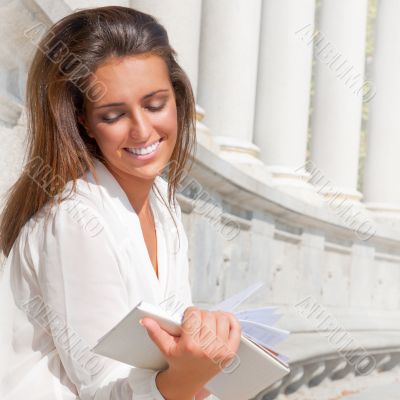 A shot of a smiling college student reading a book at park