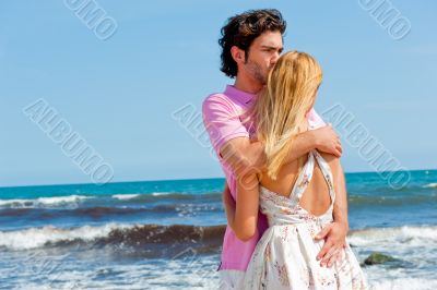 Portrait of young couple in love embracing at beach and enjoying