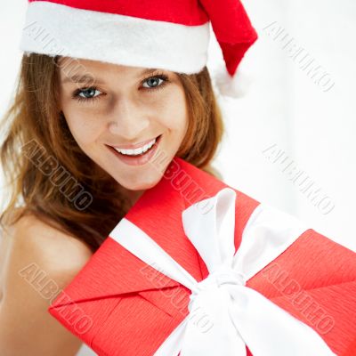 Young happy girl in Christmas hat. Standing indoors and holding 