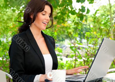 Portrait of a smiling young business woman using laptop at outdo