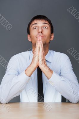 Profile shot of professional man holding hands up to face agains