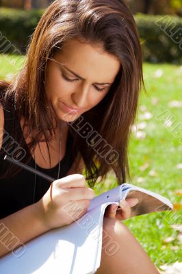 Portrait of a beautiful young female student sitting outdoor at 