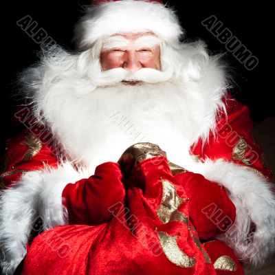 Santa sitting at the Christmas room and looking into the sack