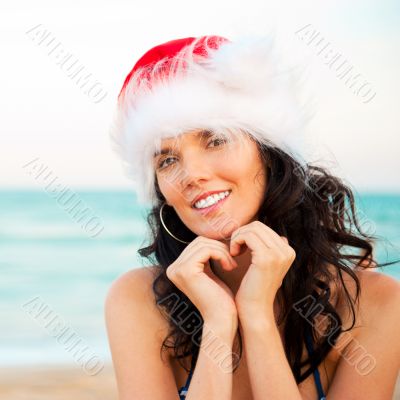 Young beautiful woman wearing christmas hat showing heart shape 