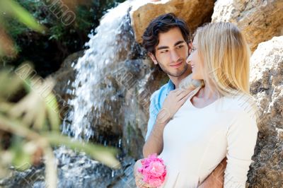 Portrait of love couple embracing outdoor in park looking happy.