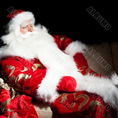Santa sitting with a sack indoor at dark night room