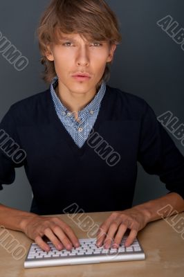 Portrait of young handsome good looking man working using keyboa