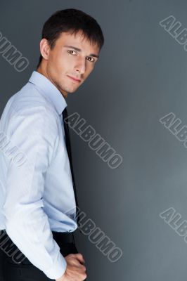 Closeup of a young smiling business man standing confidently aga