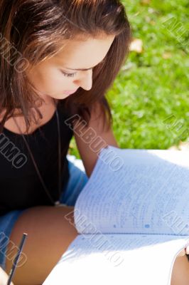 Portrait of a beautiful young female student sitting outdoor at 