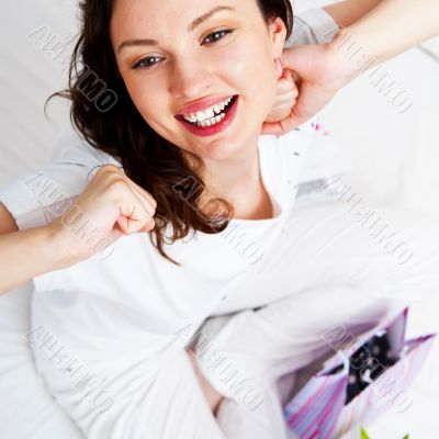 Portrait of young beautiful awake woman with gifts on bed at bed