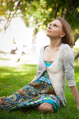 Full length of pretty young woman resting on grass and smiling. 