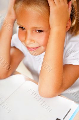 Image of smart child reading interesting book in classroom