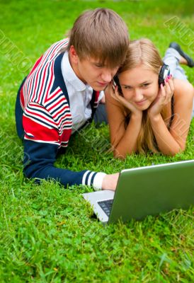 Happy young couple using laptop while lying on grass