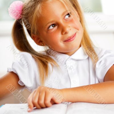 Image of smart child reading interesting book in classroom