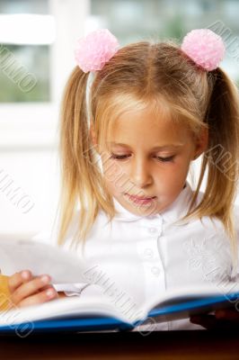 Image of smart child reading interesting book in classroom