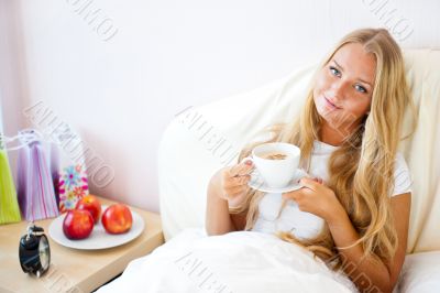 Young woman at home sipping tea or coffee from a cup
