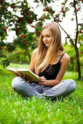Beautiful female student outdoors with a book at campus park