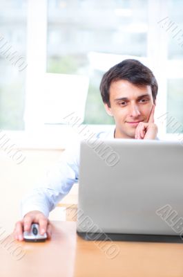 A young man sitting in front of a laptop in his office