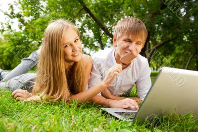 College students using laptop on campus lawn