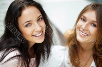Two women whispering and smiling while shopping inside mall