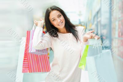 Photo of young joyful woman with shopping bags on the background