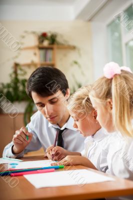 Teacher helping students with schoolwork in school classroom. Ve