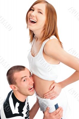 Cheerful man listening the belly of his pregnant wife and laughi