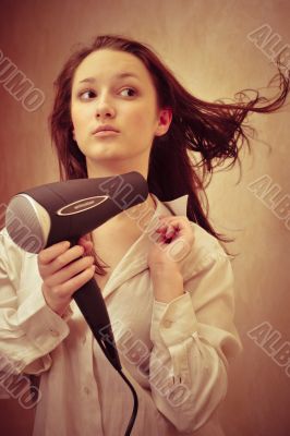 Beautiful woman drying her hair with hairdryer