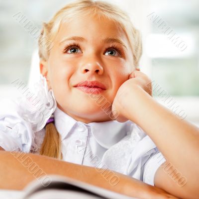 Image of smart child reading interesting book in classroom