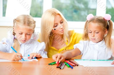 Young pretty teacher helping to her students to make exercise in