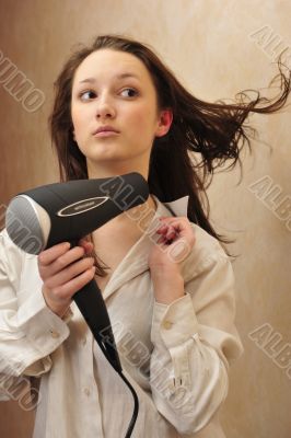 Beautiful woman drying her hair with hairdryer