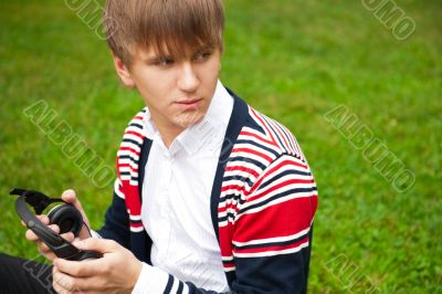 Student outside sitting on green grass and listening music via h