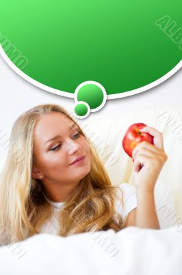 Young beautiful woman with apple in bed in the morning
