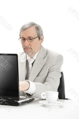 Portrait of an older businessman with a computer and a cup.