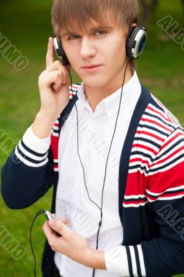 Student listening language course in headphones outside school