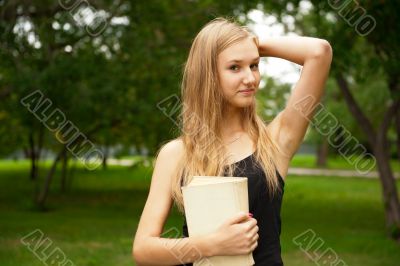 Beautiful female student outdoors with a book at campus park