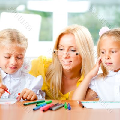 Young pretty teacher helping to her students to make exercise in