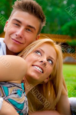 Portrait of beautiful young couple sitting on ground in park rel