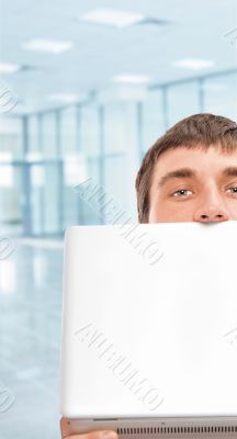 Portrait of a young man with a computer, hiding his face.