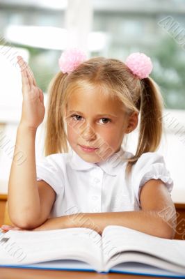 Portrait of a young girl in school at the desk.