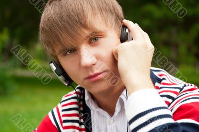 Student outside sitting on green grass and listening music via h