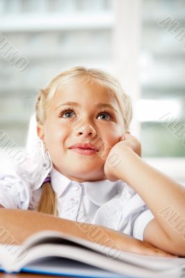Image of smart child reading interesting book in classroom