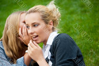 Two women whispering and smiling