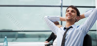Portrait of a handsome young business man leaning against the wi
