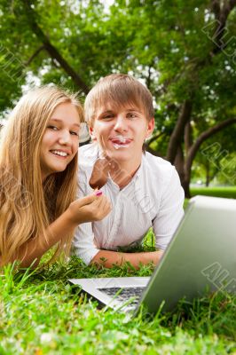 College students using laptop on campus lawn