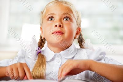 Portrait of a young girl in school at the desk.