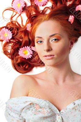 Beautiful woman with flowers in her red hair she is lying relaxe