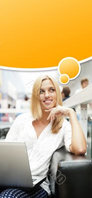 Portrait of happy blond woman using laptop at shopping mall cafe