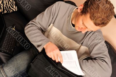 Happy young man sitting on sofa at home 