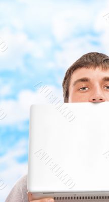 Young man holding laptop near his face outdoor